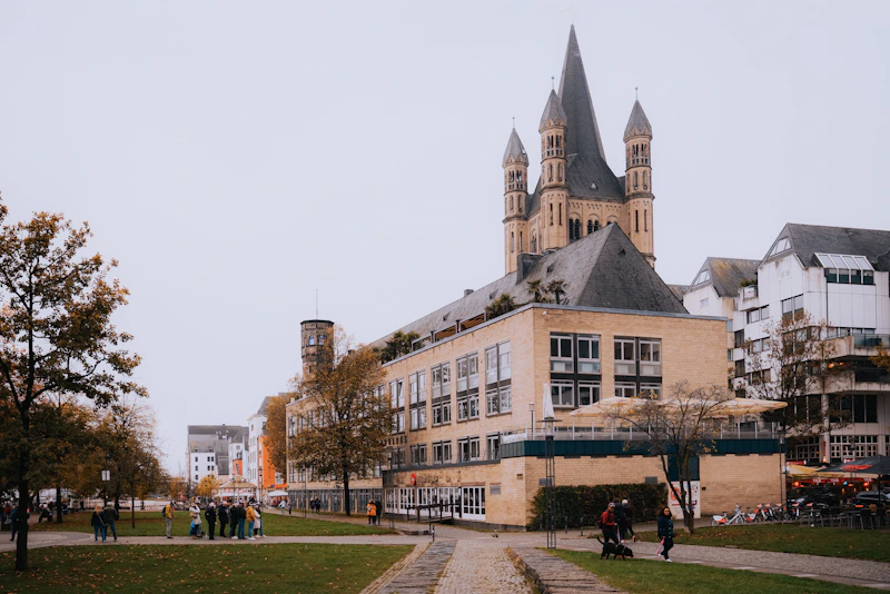 A group of people walking down a sidewalk next to a tall building