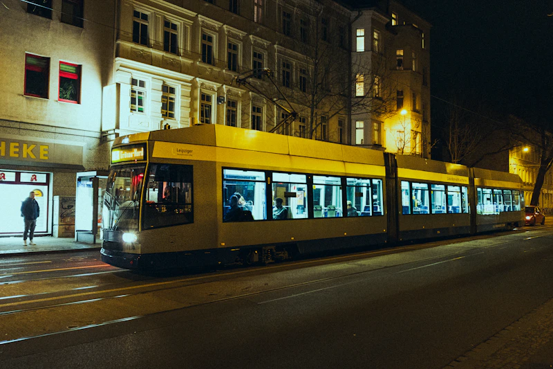 A lit tram travels down a street at night.